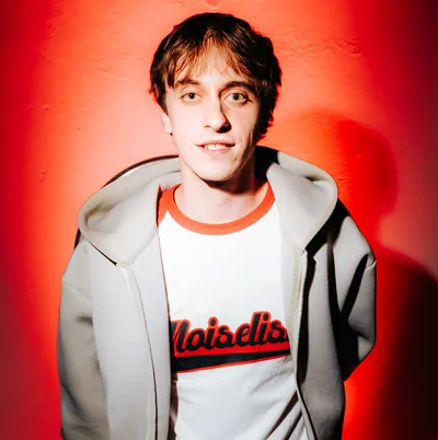 Ragazzo con la felpa grigia davanti alla luce rossa al DumBO